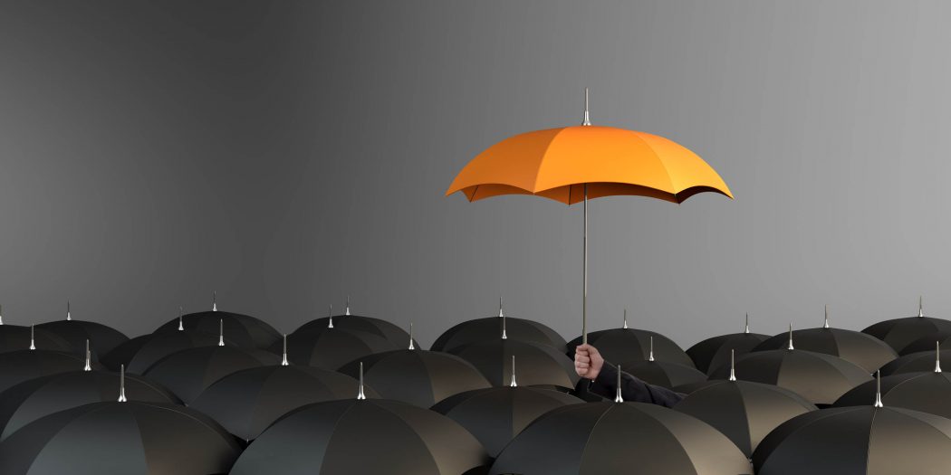 orange-colored-umbrella-between-the-black-umbrellas