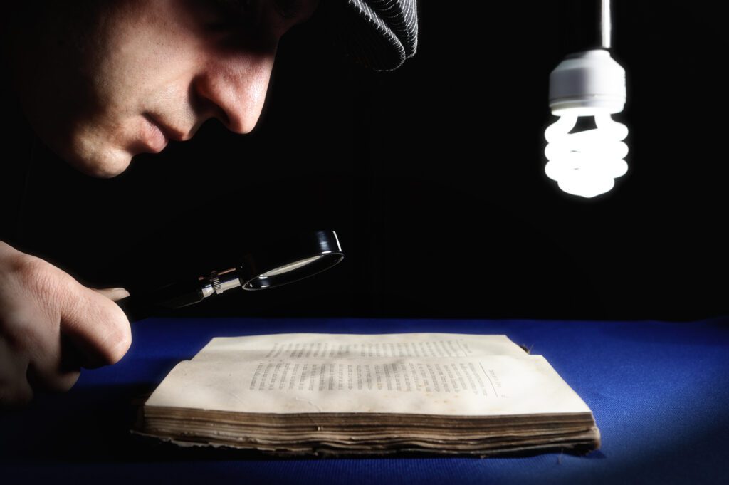 man-looking-to-an-old-book-through-magnifying-glass