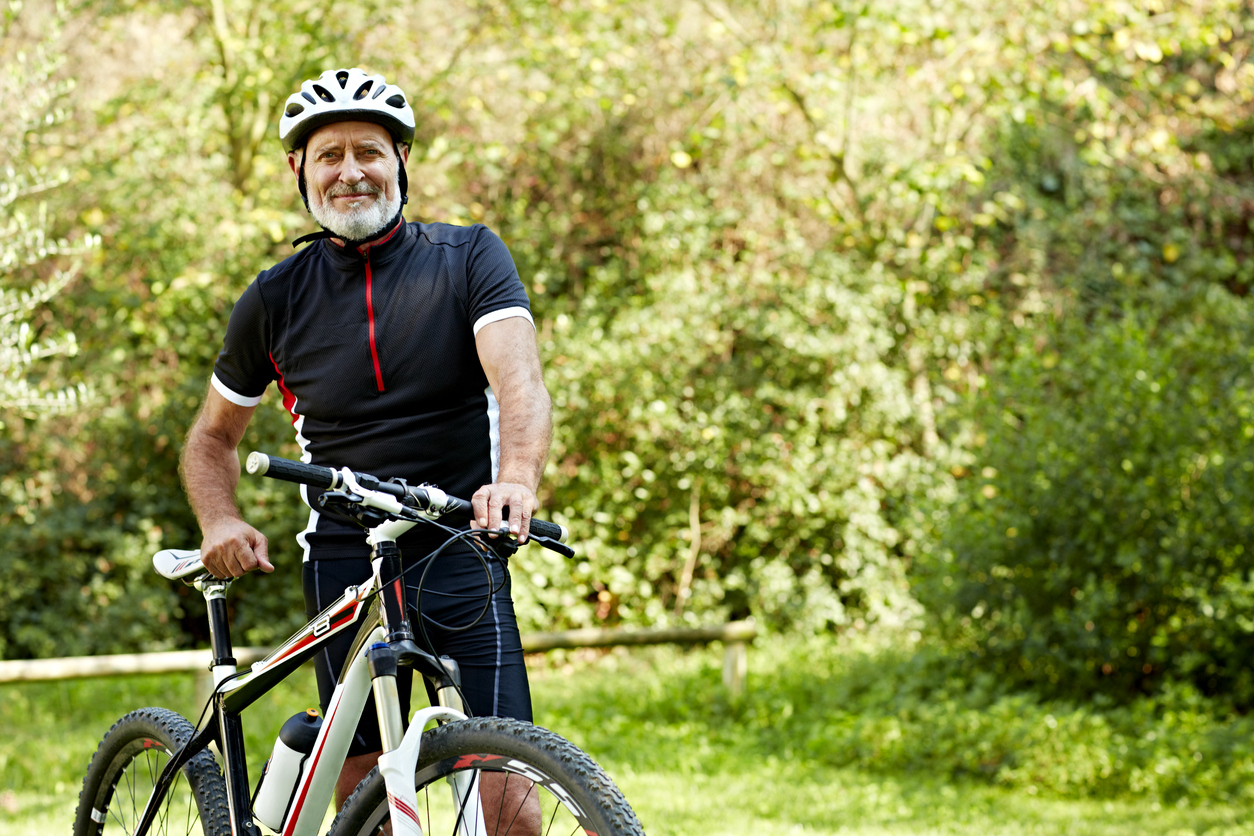 confident-senior-man-with-bicycle-in-park